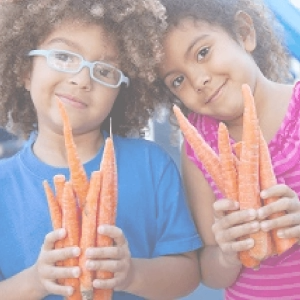 Two young girls holding carrots